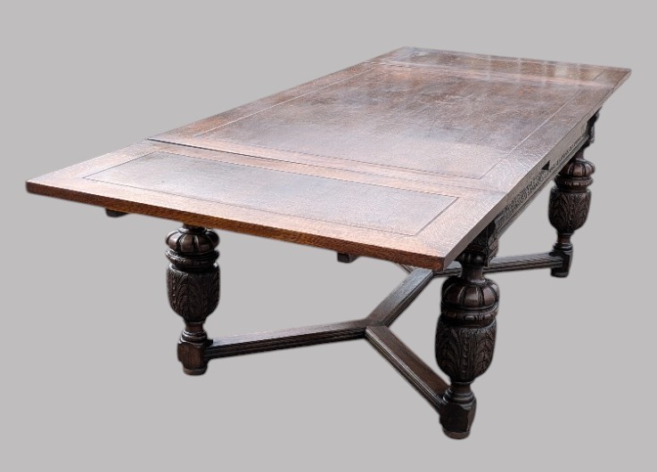 A rectangular extending oak dining table showing a quarter-sawn timber surface and carved bulbous legs underneath. View XII