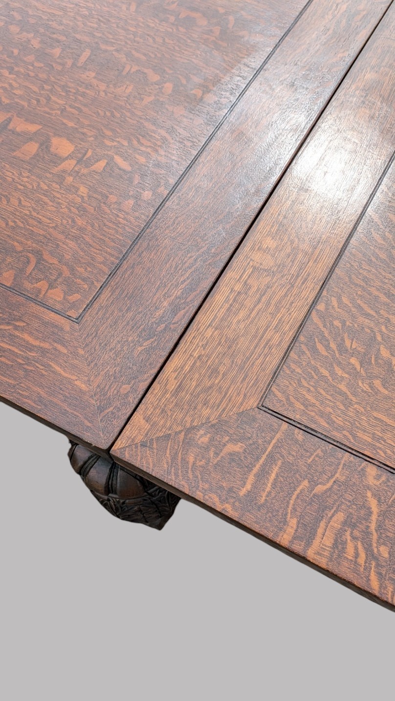 A rectangular extending oak dining table showing a quarter-sawn timber surface and carved bulbous legs underneath. View XIII