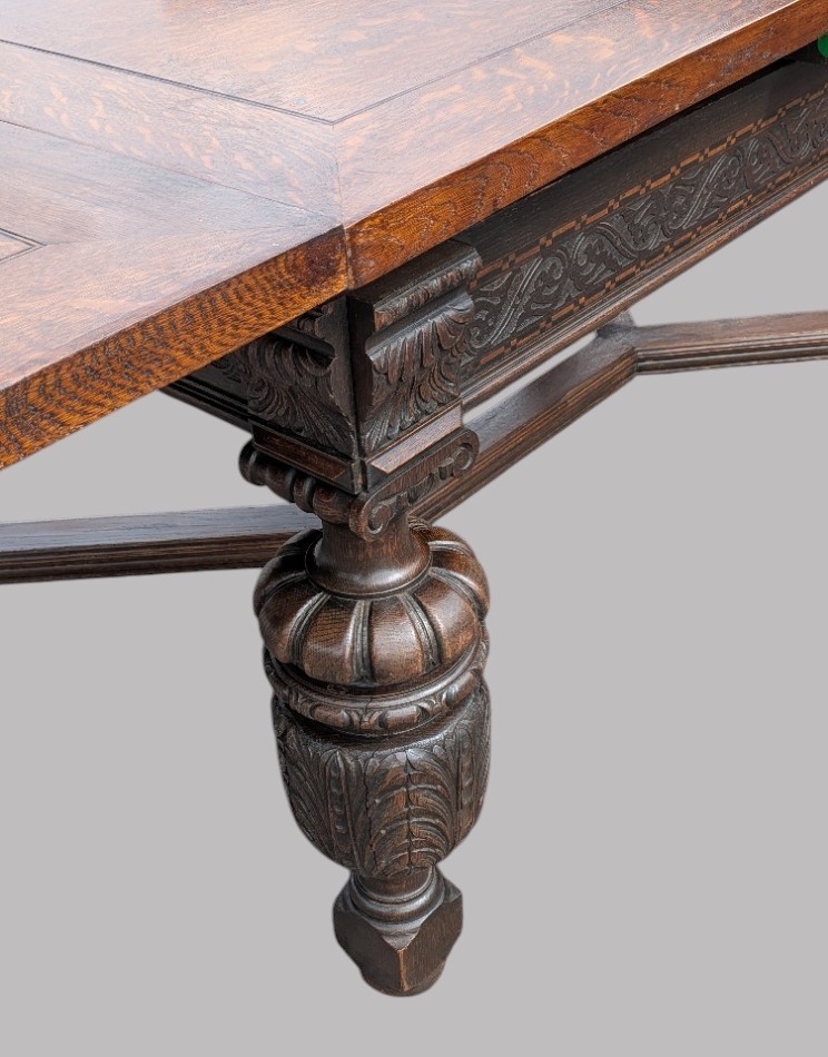 A rectangular extending oak dining table showing a quarter-sawn timber surface and carved bulbous legs underneath. View XIV