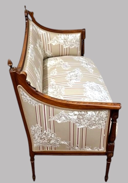 An Edwardian walnut drawing room sofa featuring a sweeping curved backrest, turned front supports, slender tapered legs, and cream striped patterned upholstery. View II