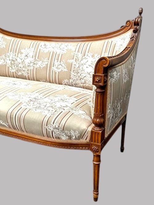 An Edwardian walnut drawing room sofa featuring a sweeping curved backrest, turned front supports, slender tapered legs, and cream striped patterned upholstery. View V