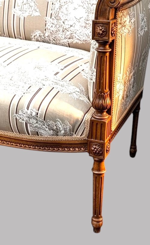 An Edwardian walnut drawing room sofa featuring a sweeping curved backrest, turned front supports, slender tapered legs, and cream striped patterned upholstery. View VI