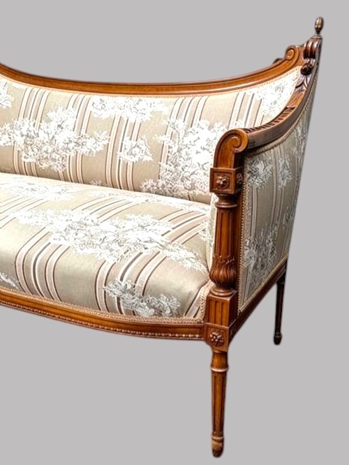 An Edwardian walnut drawing room sofa featuring a sweeping curved backrest, turned front supports, slender tapered legs, and cream striped patterned upholstery. View VII