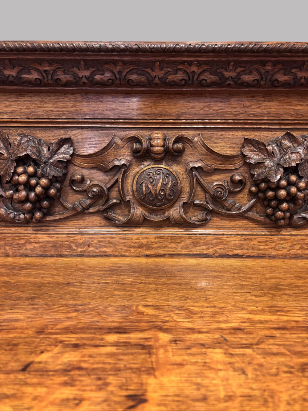 A carved dark oak Victorian sideboard featuring a raised back gallery, relief fruit carvings, barley twist columns, and two pedestal cupboards flanking an open centre. View II