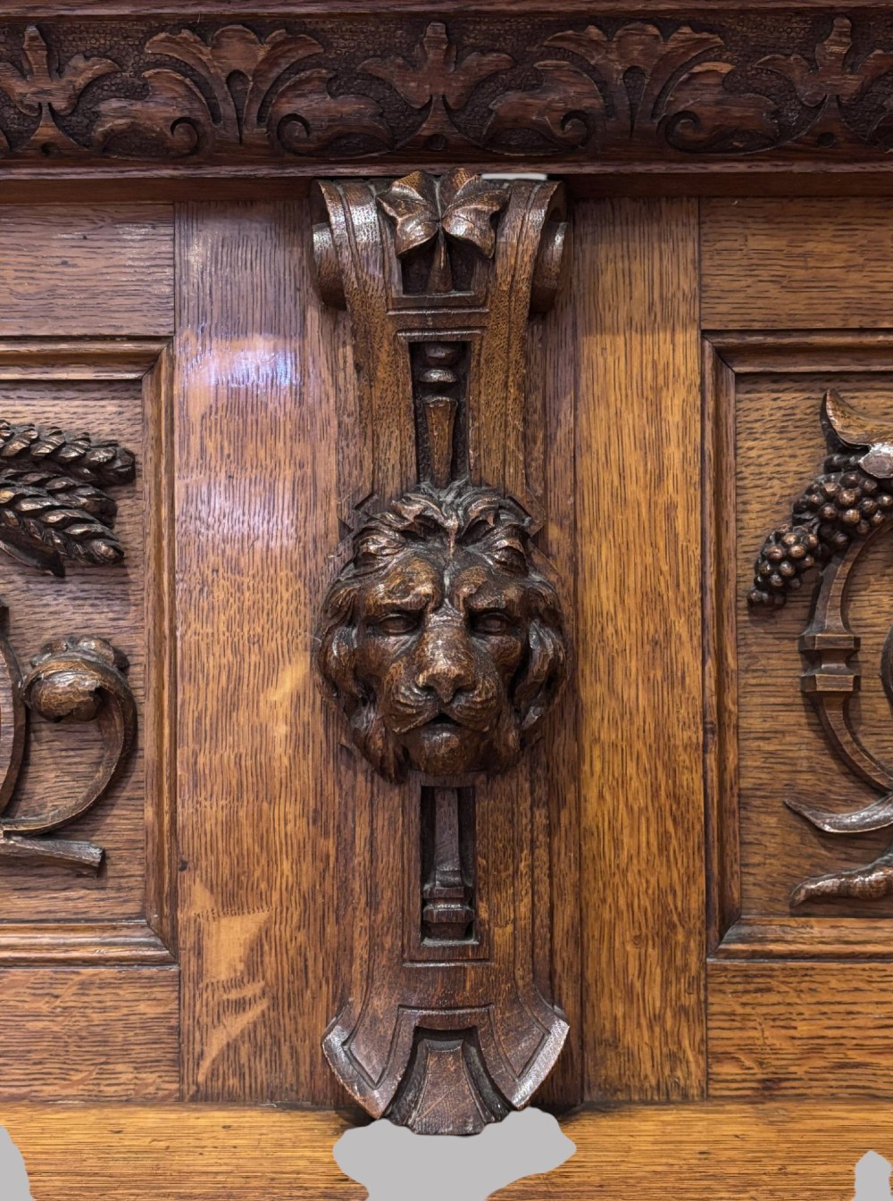 A carved dark oak Victorian sideboard featuring a raised back gallery, relief fruit carvings, barley twist columns, and two pedestal cupboards flanking an open centre. View III