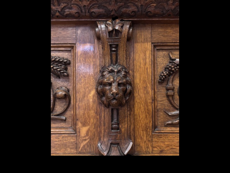 A carved dark oak Victorian sideboard featuring a raised back gallery, relief fruit carvings, barley twist columns, and two pedestal cupboards flanking an open centre. View VIII