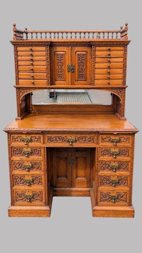 A late Victorian carved oak kneehole desk featuring an upper gallery with drawers, spindles, carved doors, and a pedestal base. View III