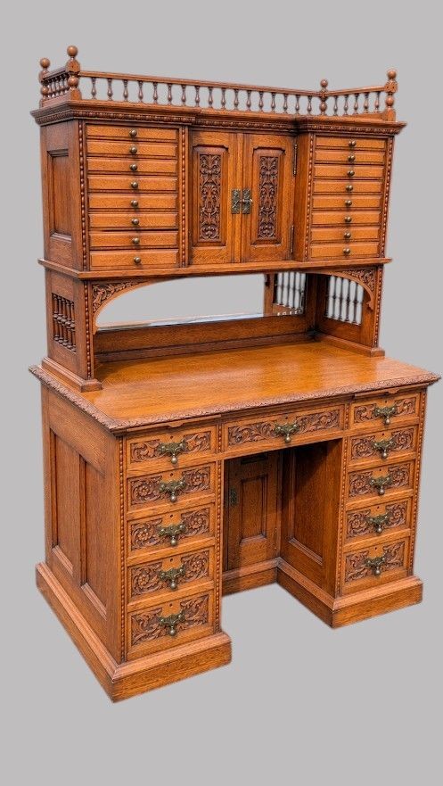 A late Victorian carved oak kneehole desk featuring an upper gallery with drawers, spindles, carved doors, and a pedestal base. View IV