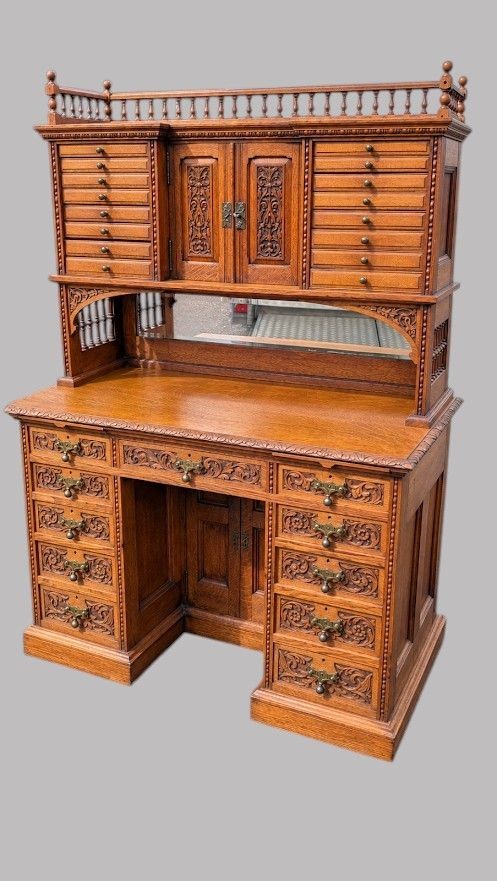 A late Victorian carved oak kneehole desk featuring an upper gallery with drawers, spindles, carved doors, and a pedestal base. View V
