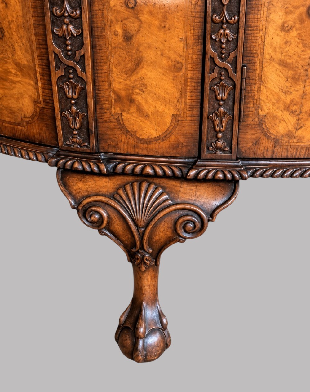 A bow-front burr walnut sideboard with carved pilasters, twin cupboard doors, a top drawer, and four carved cabriole legs ending in ball and claw feet. View III