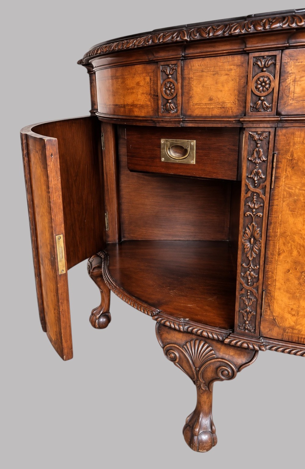 A bow-front burr walnut sideboard with carved pilasters, twin cupboard doors, a top drawer, and four carved cabriole legs ending in ball and claw feet. View IV