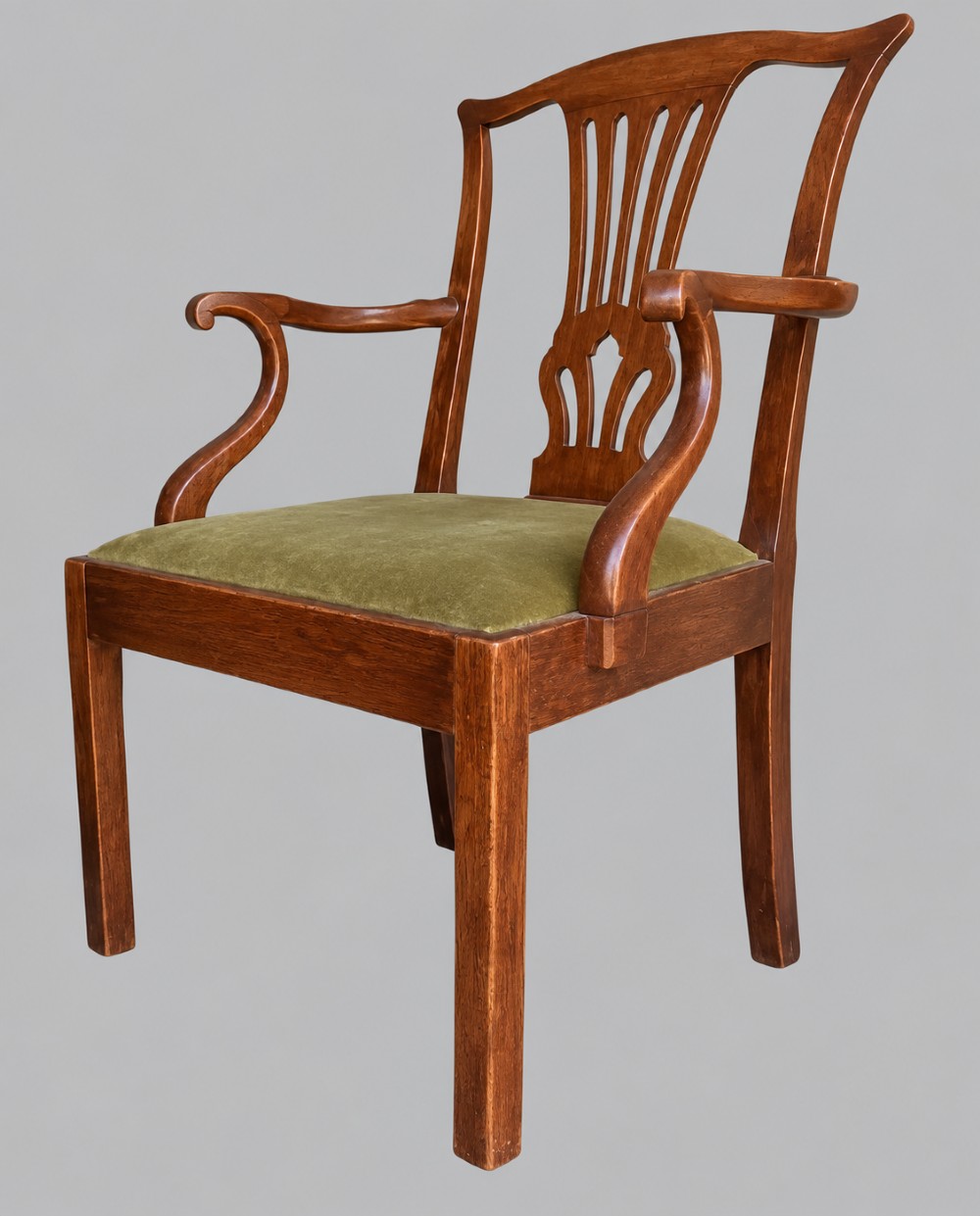 A Georgian Chippendale style mahogany elbow chair with a pierced splat back, shaped arms, and a green velvet seat. View II