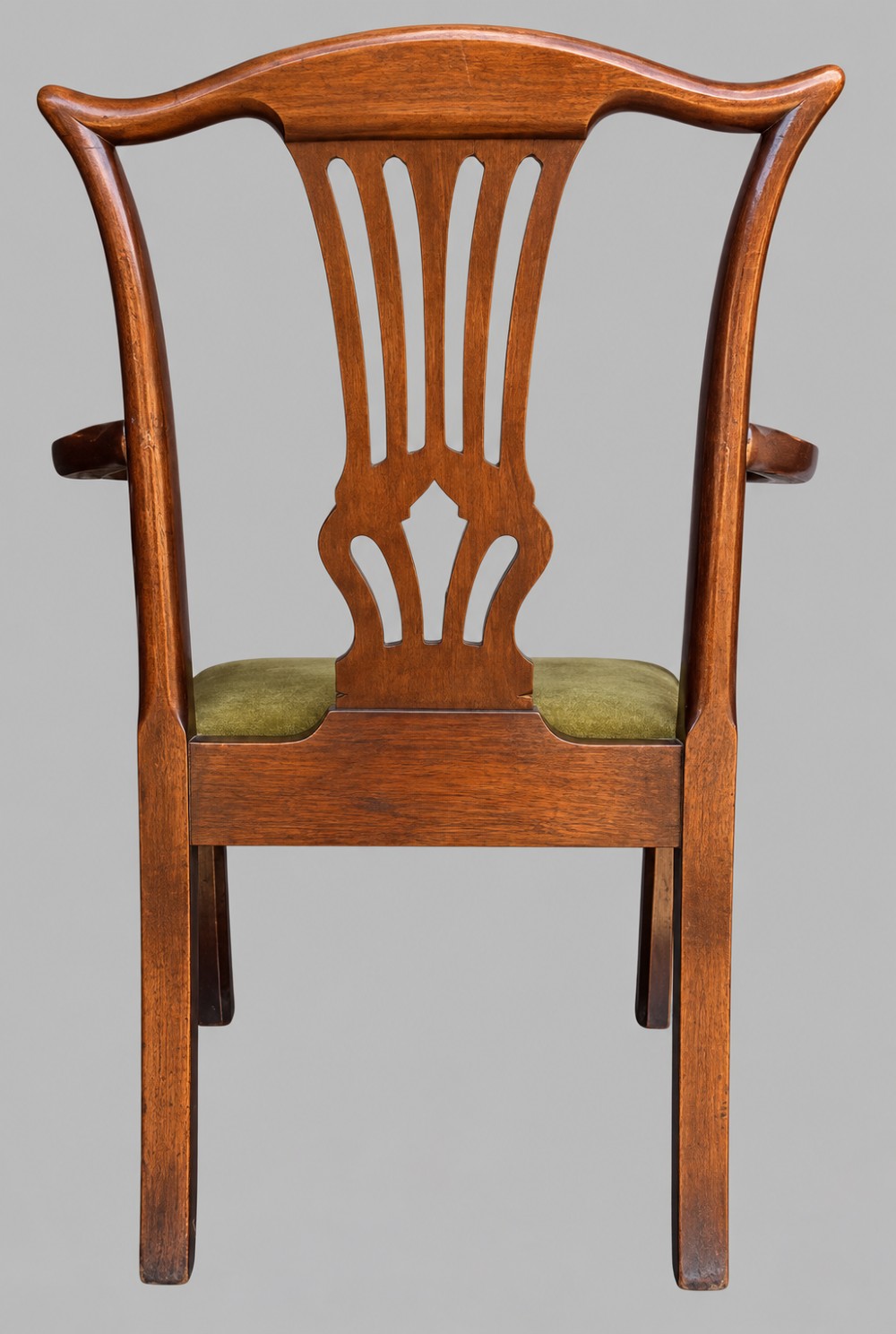 A Georgian Chippendale style mahogany elbow chair with a pierced splat back, shaped arms, and a green velvet seat. View V