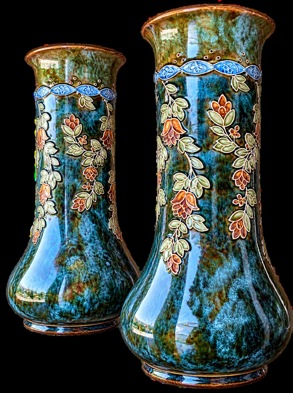 A pair of tall Art Nouveau stoneware vases featuring mottled teal and brown glazes with raised floral and leaf decoration. View V