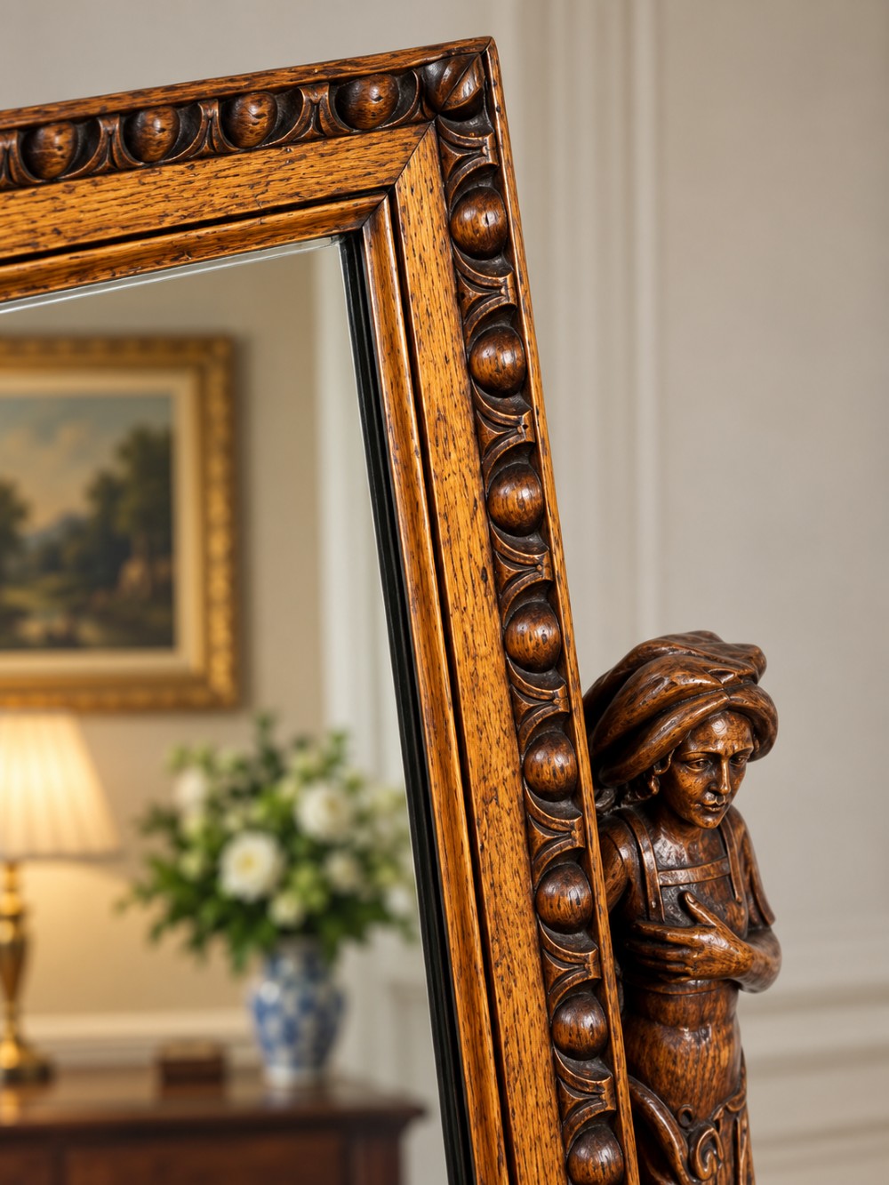 A carved oak dressing mirror featuring a rectangular frame flanked by two carved human figures resting on an ornate plinth base. View VI