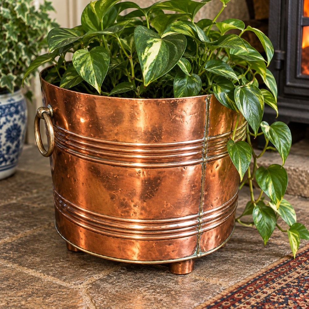 A cylindrical Victorian copper log bin featuring raised horizontal ribs, brass drop ring handles, and short metal feet. View IV