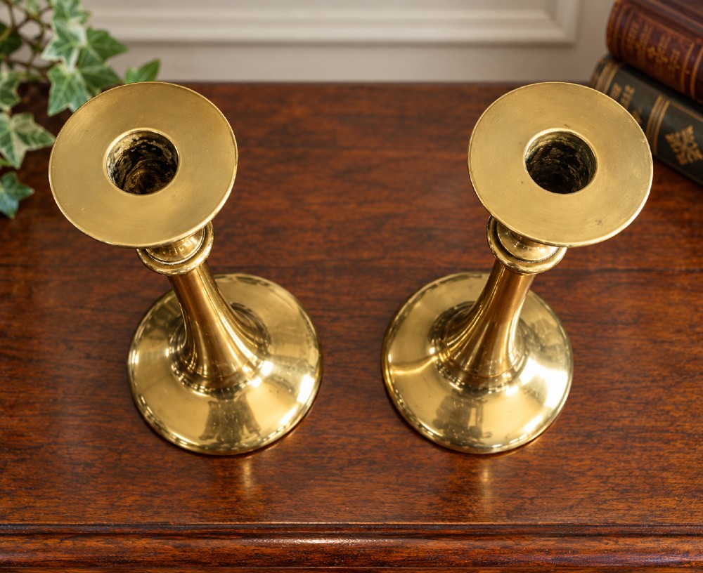 A pair of polished brass Art Nouveau candlesticks featuring tall flared stems and wide circular bases. View III