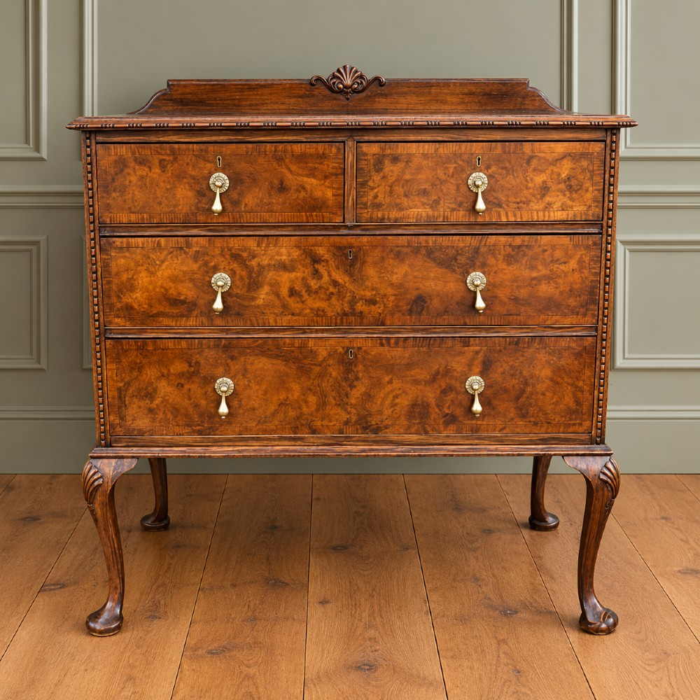 A Queen Anne style burr walnut chest of drawers featuring two short over two long drawers, brass drop handles, and carved cabriole legs.