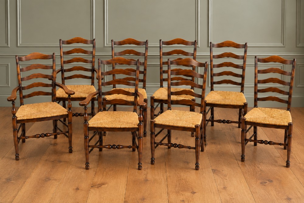 A set of eight dark wood ladderback dining chairs with hand-woven rush seats, including two armchairs and six side chairs.