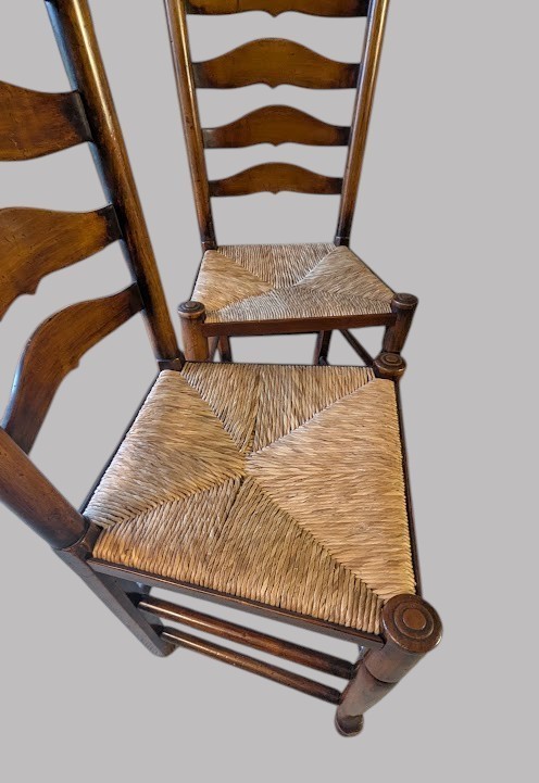 A set of eight dark wood ladderback dining chairs with hand-woven rush seats, including two armchairs and six side chairs. View IX
