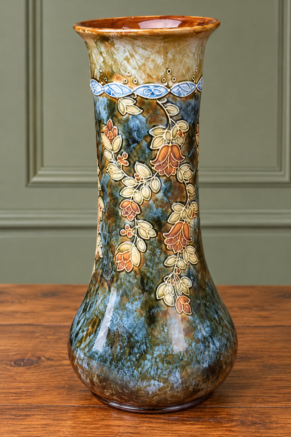 A pair of tall stoneware vases featuring mottled teal-blue glaze and raised relief trailing floral decoration with flared necks and bulbous bases. View II