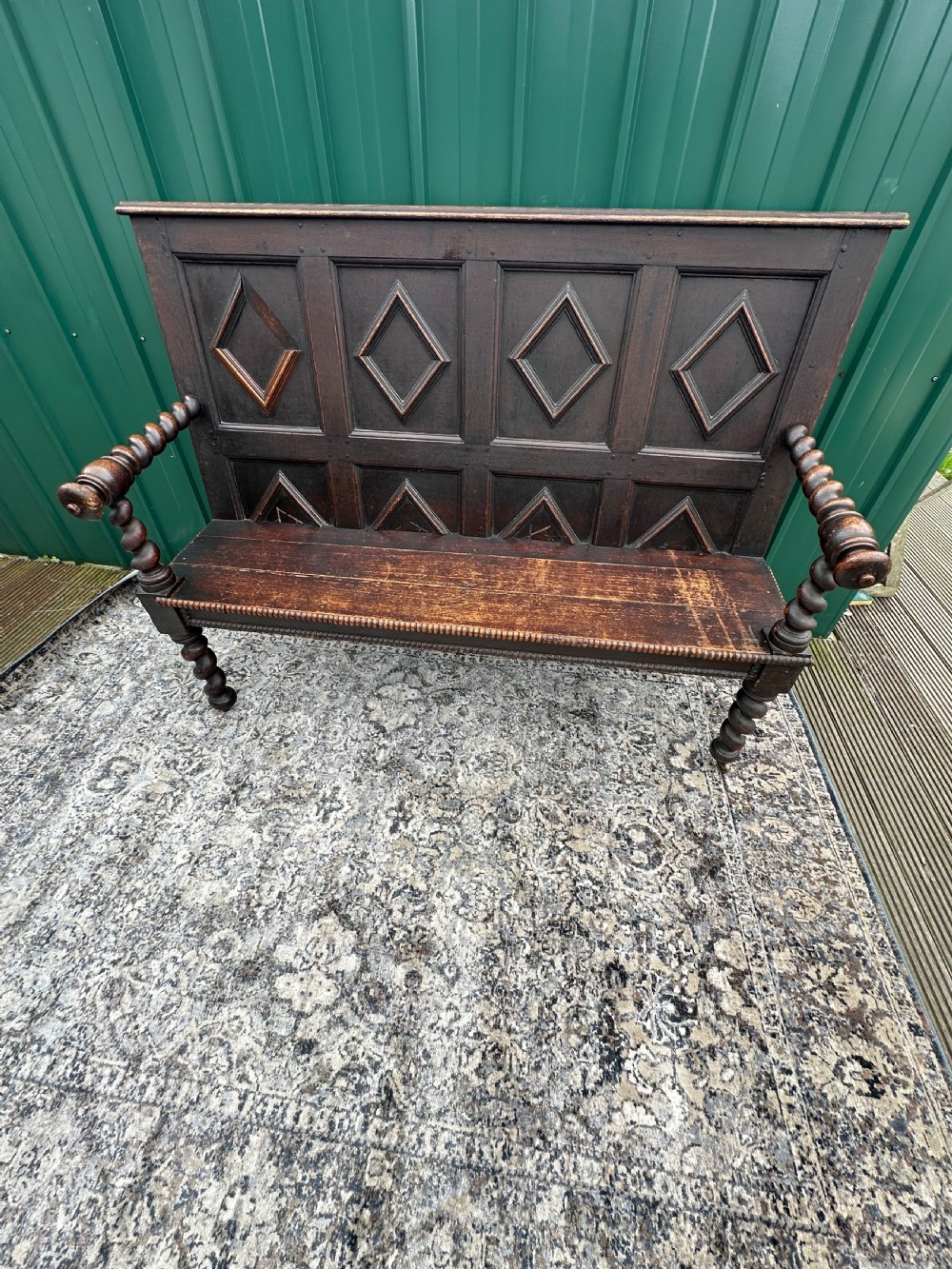 A dark oak 19th-century settle featuring a four-panel back with geometric diamond moulding, barley twist supports, and small brass castors. View VIII