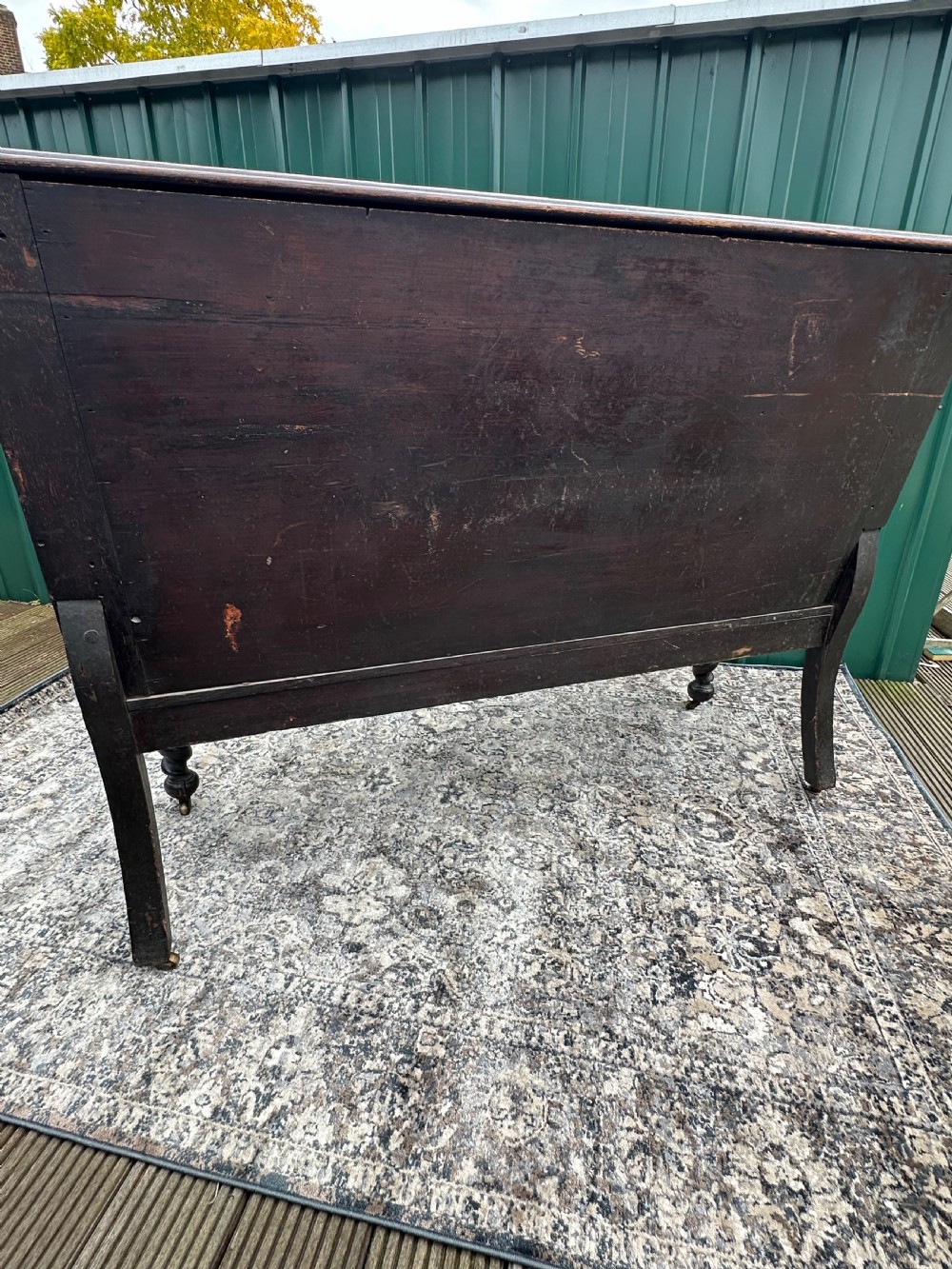 A dark oak 19th-century settle featuring a four-panel back with geometric diamond moulding, barley twist supports, and small brass castors. View IX