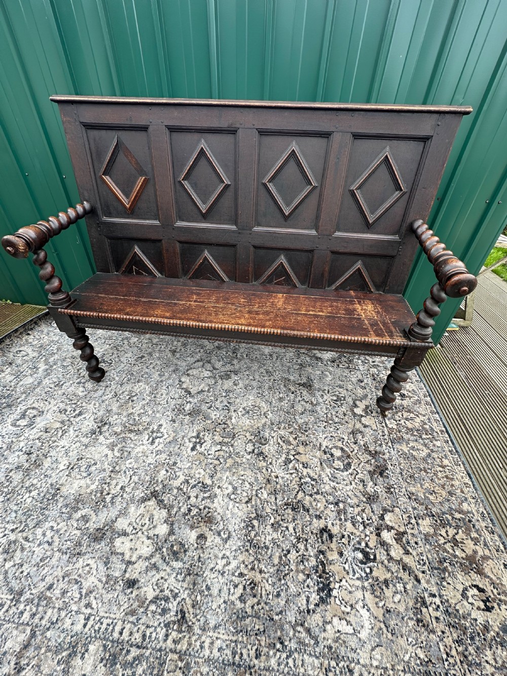 A dark oak 19th-century settle featuring a four-panel back with geometric diamond moulding, barley twist supports, and small brass castors. View XI