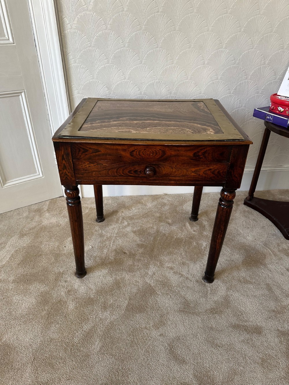 A dark brown Victorian wooden side table with turned legs, a single drawer, and an inset brown marble top with a brass frame.