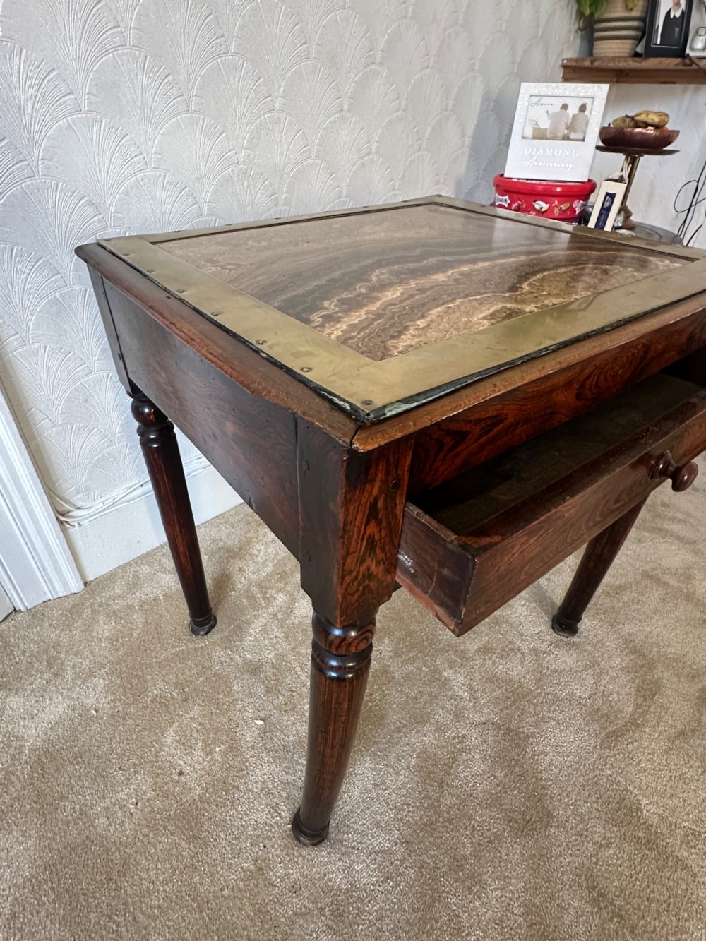 A dark brown Victorian wooden side table with turned legs, a single drawer, and an inset brown marble top with a brass frame. View X