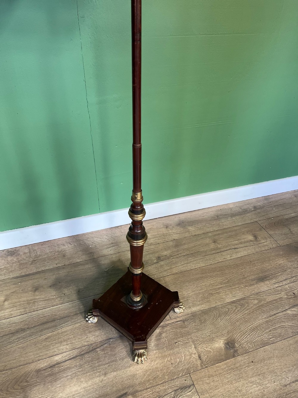 An antique Regency pole fire screen featuring an octagonal pokerwork panel supported on a turned wooden column with a plinth base resting on brass claw feet. View II