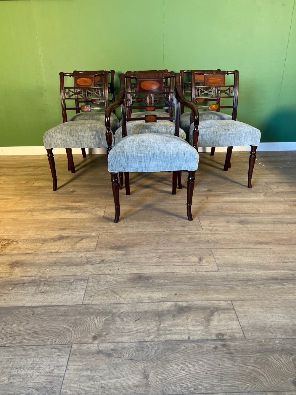 A set of seven Regency mahogany dining chairs with inlaid geometric backs and pale blue upholstered seats, featuring one carver armchair.