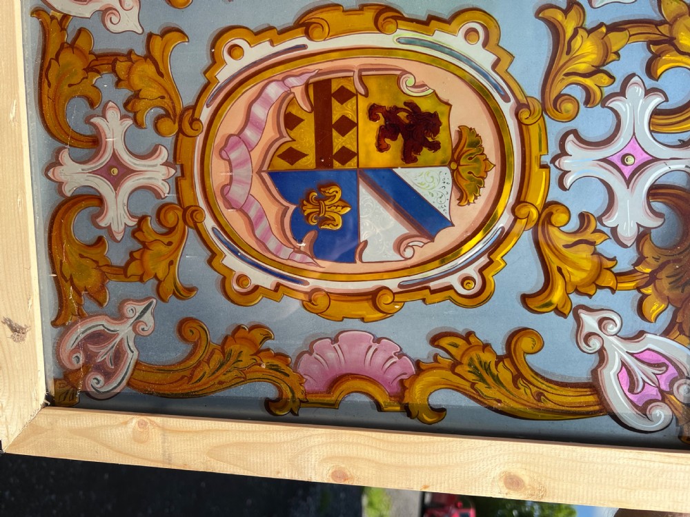 Rectangular painted glass panel featuring a central coat of arms inside an oval cartouche with scrolling acanthus leaf ornament, framed in light pine wood. View III