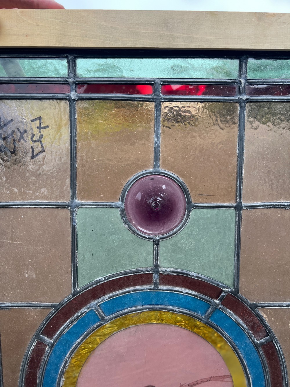 A rectangular Victorian stained glass panel featuring a hand-painted central medallion of a bird surrounded by geometric glass borders and purple roundels, housed in a pine frame. View III
