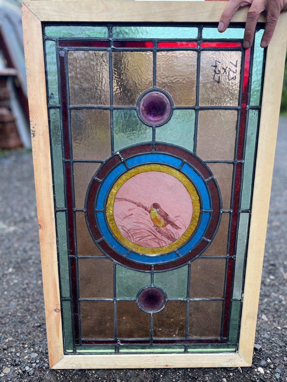 A rectangular Victorian stained glass panel featuring a hand-painted central medallion of a bird surrounded by geometric glass borders and purple roundels, housed in a pine frame. View IV