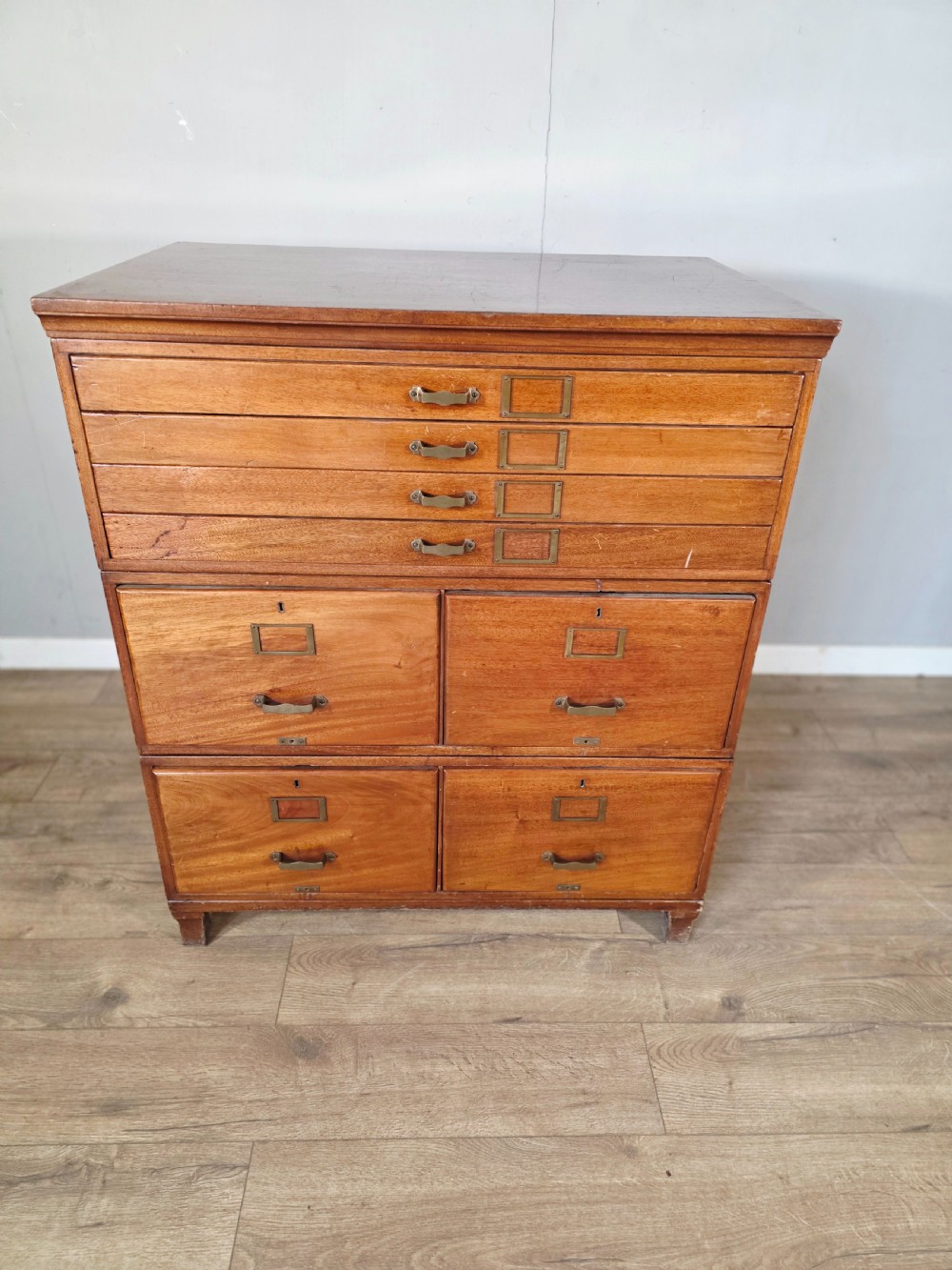 A vintage wooden sectional plan chest with multiple shallow and deep drawers fitted with brass pulls.
