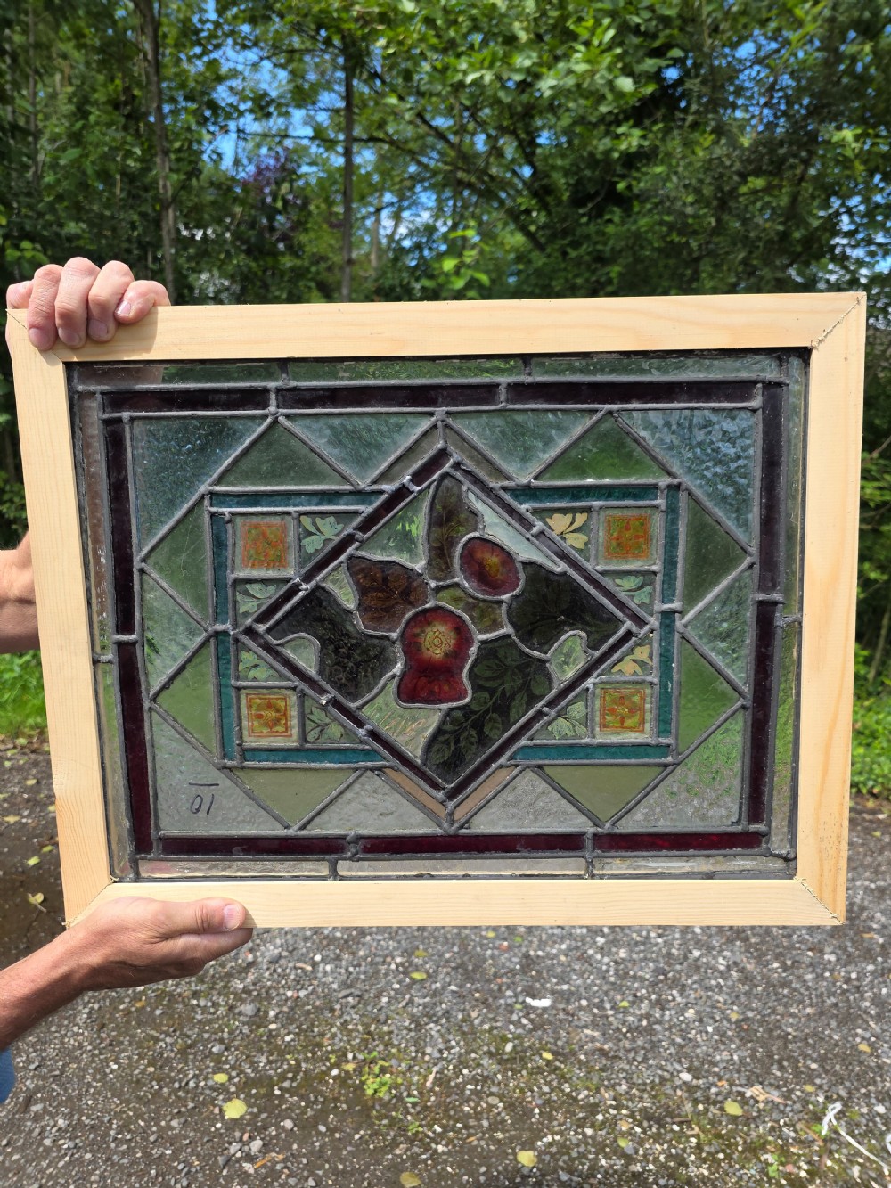 A rectangular late Victorian leaded glass window panel featuring central hand-painted floral motifs inside a geometric lead came frame with green and dark glass borders.