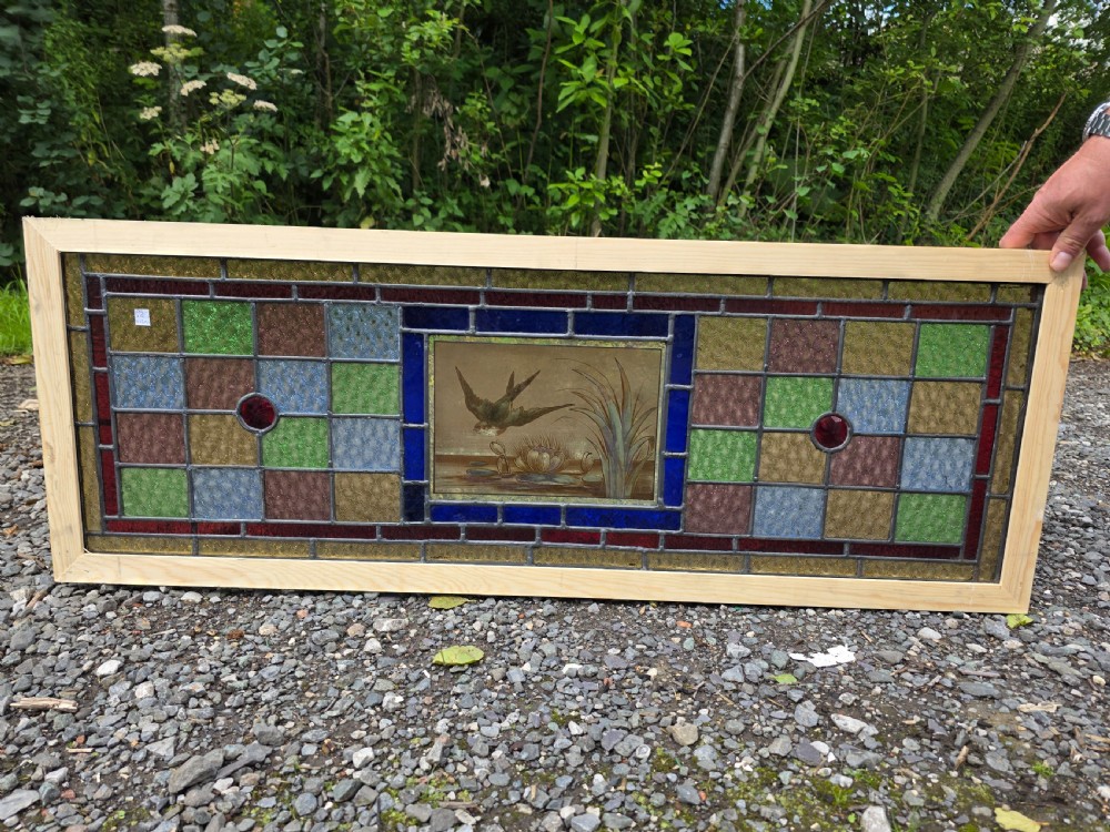 A rectangular antique leaded glass panel featuring a hand-painted central scene of a bird in flight over water lilies, surrounded by geometric colourful glass panes. View II