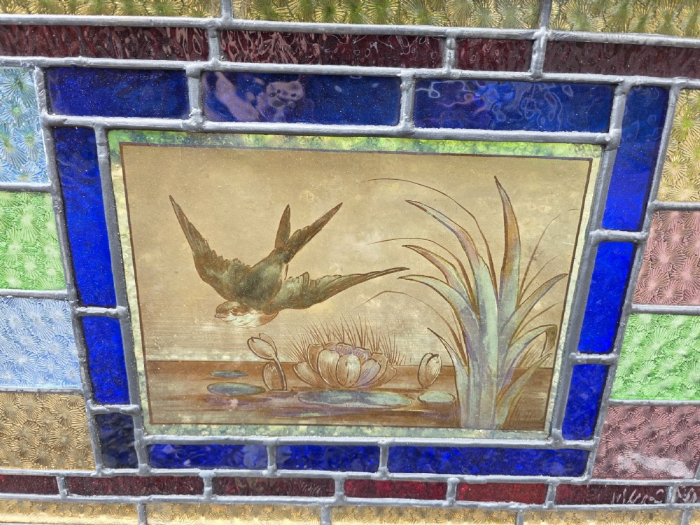 A rectangular antique leaded glass panel featuring a hand-painted central scene of a bird in flight over water lilies, surrounded by geometric colourful glass panes. View III