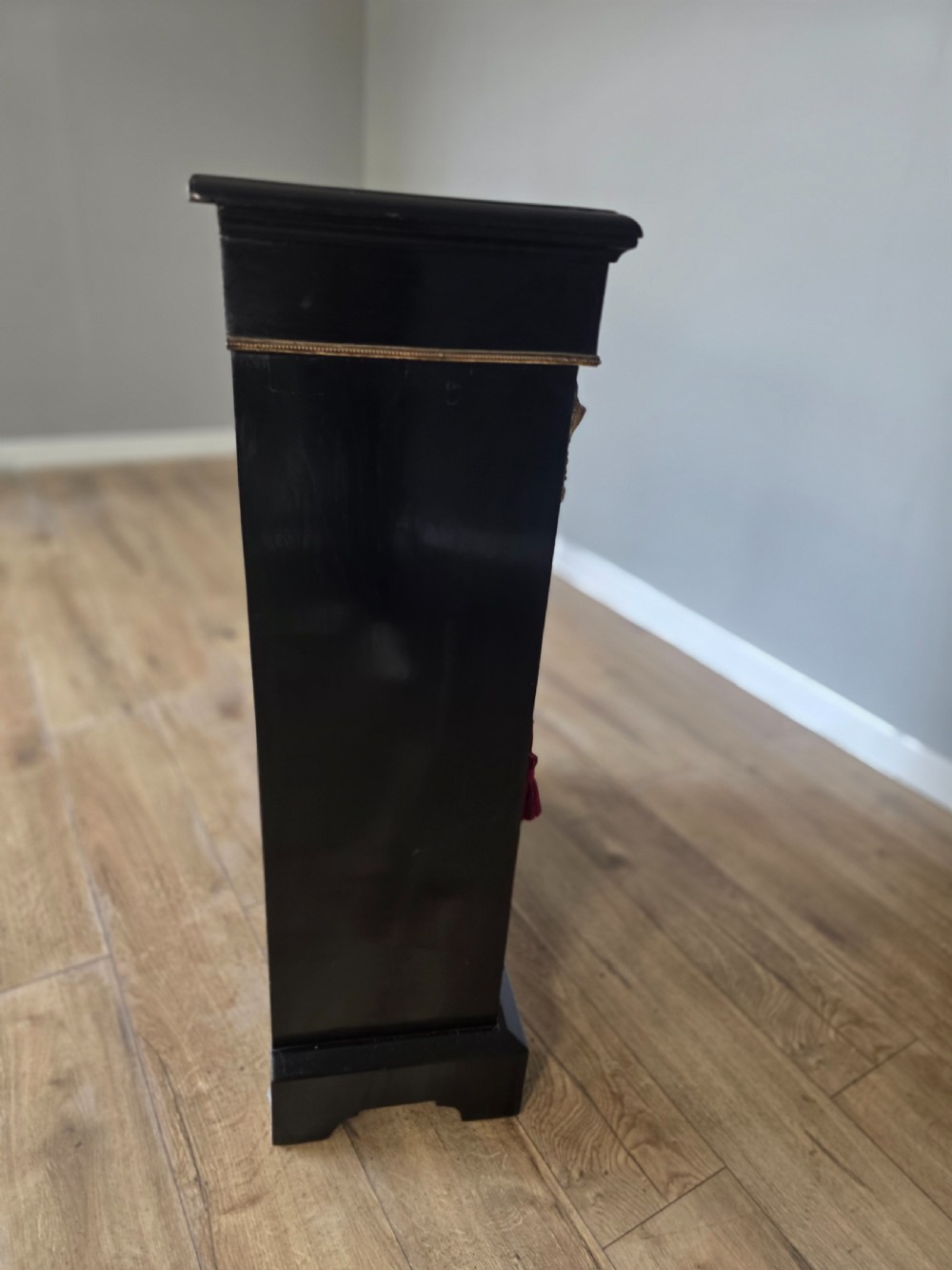 A pair of Victorian ebonised wooden pier cabinets featuring single glazed doors, gilt metal ormolu corner mounts, and oval porcelain plaques. View XIX