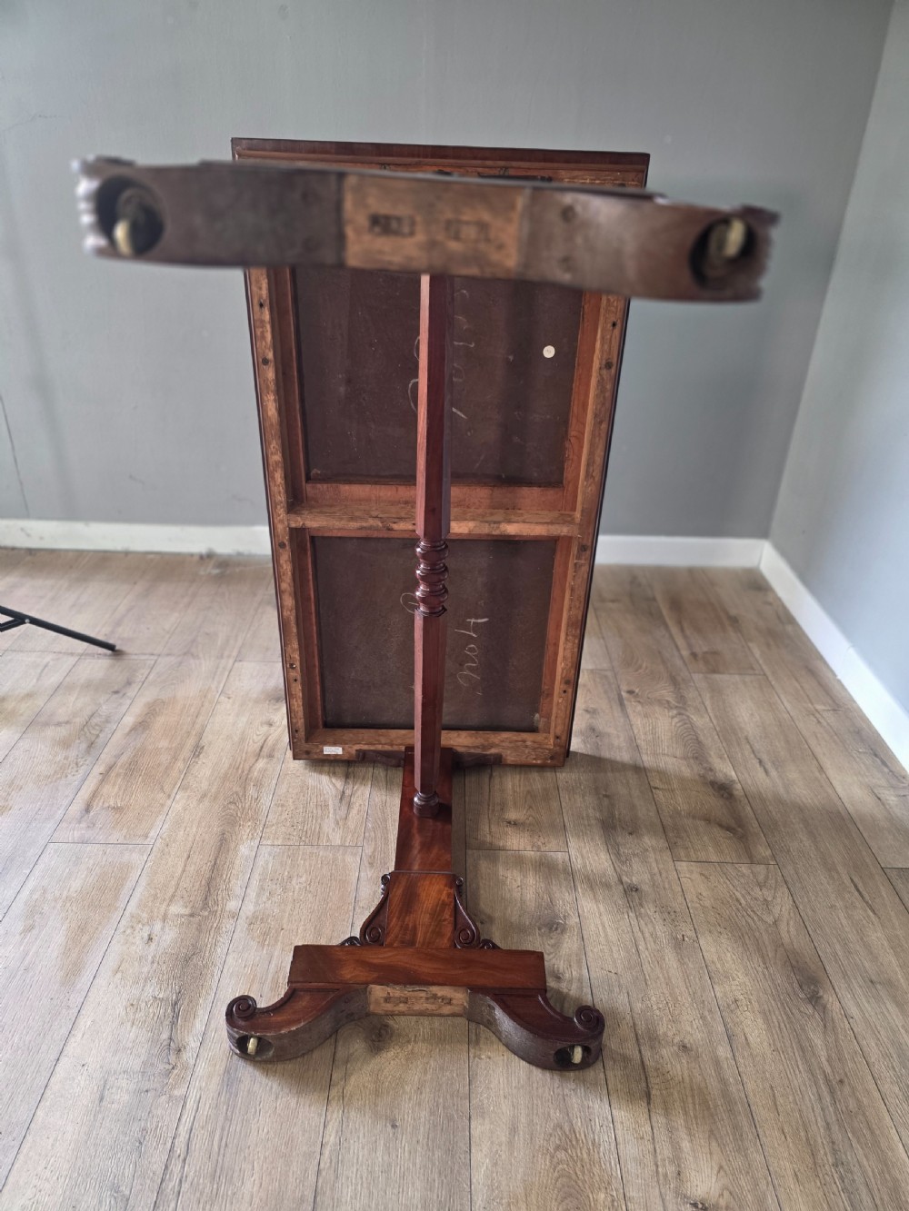 An early Victorian mahogany side table featuring a rectangular top, a central turned stretcher, and carved trestle feet resting on a light wood floor. View XV