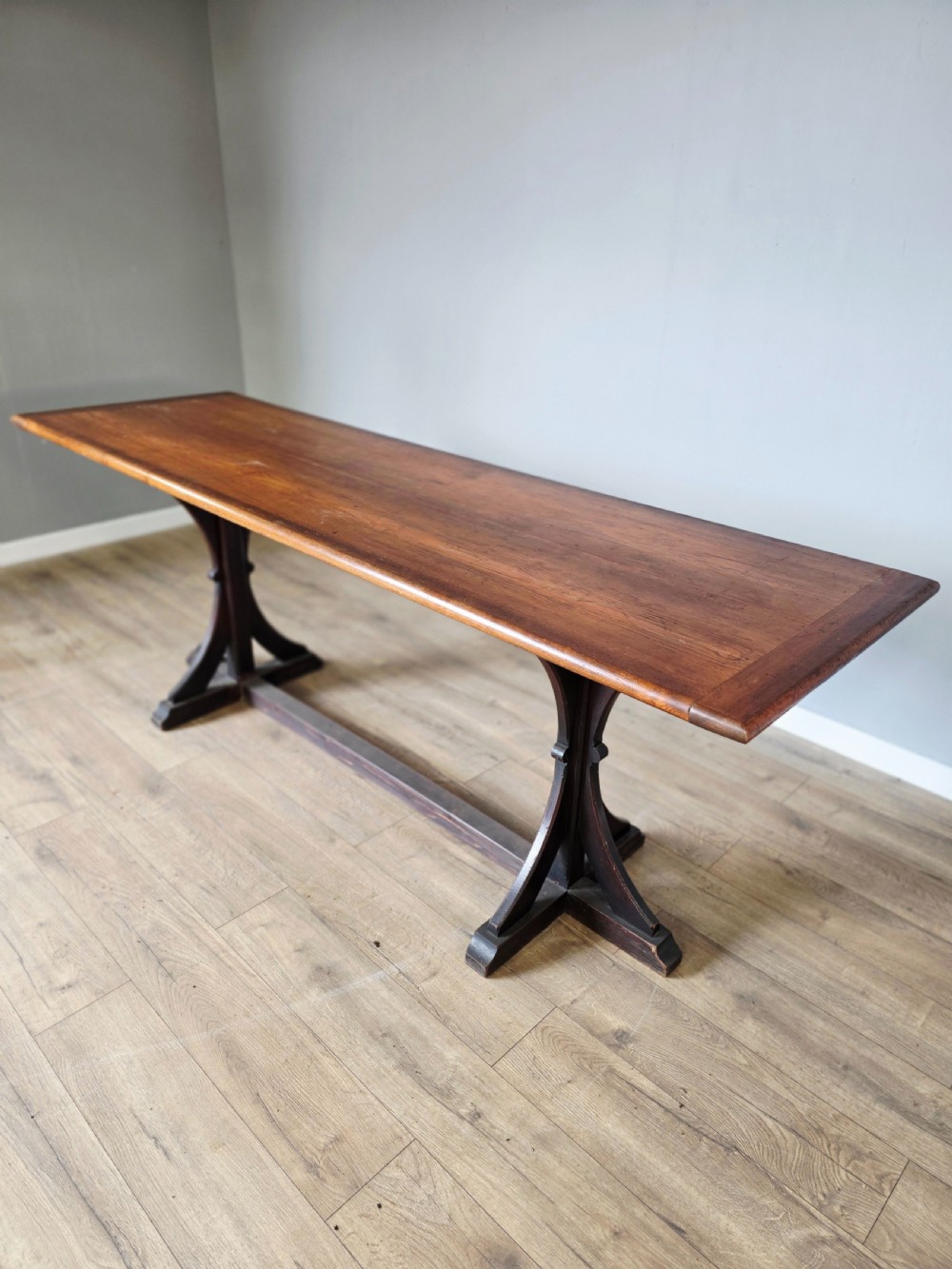 A long Victorian pitch pine centre serving table featuring a smooth rectangular top supported by curved trestle legs and a central stretcher base. View III