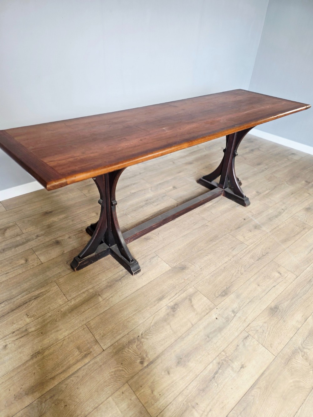 A long Victorian pitch pine centre serving table featuring a smooth rectangular top supported by curved trestle legs and a central stretcher base. View IV