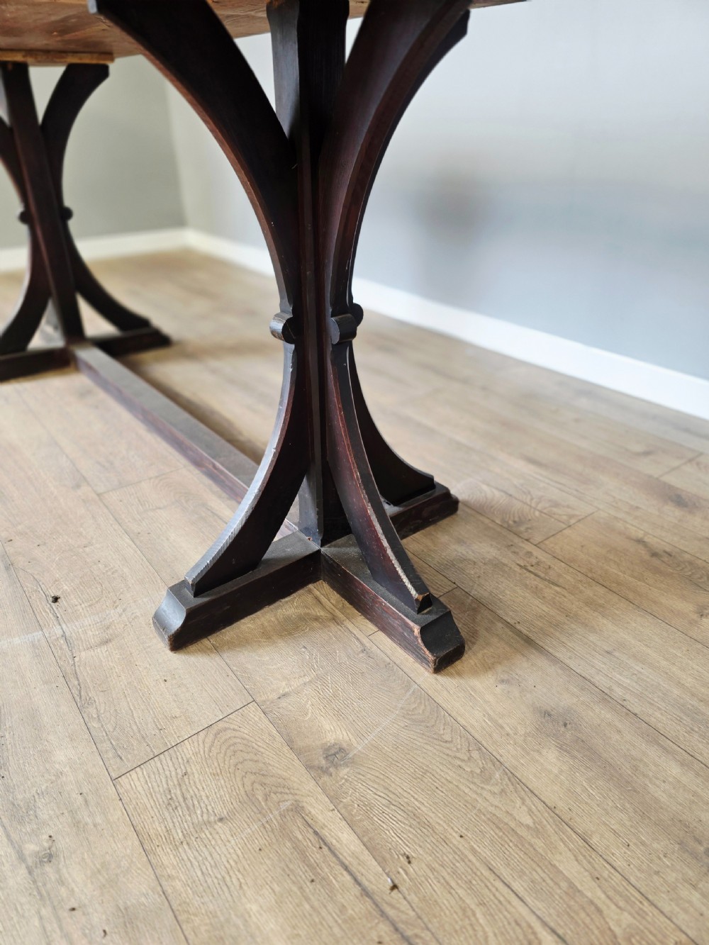 A long Victorian pitch pine centre serving table featuring a smooth rectangular top supported by curved trestle legs and a central stretcher base. View VII
