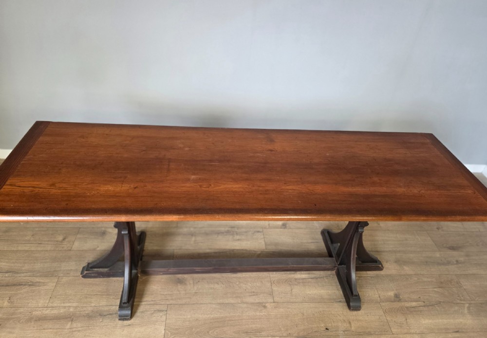 A long Victorian pitch pine centre serving table featuring a smooth rectangular top supported by curved trestle legs and a central stretcher base. View IX