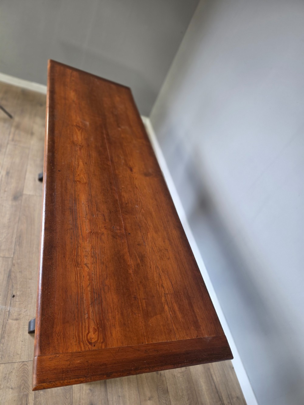 A long Victorian pitch pine centre serving table featuring a smooth rectangular top supported by curved trestle legs and a central stretcher base. View X