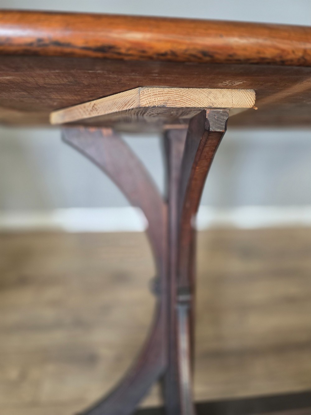 A long Victorian pitch pine centre serving table featuring a smooth rectangular top supported by curved trestle legs and a central stretcher base. View XI