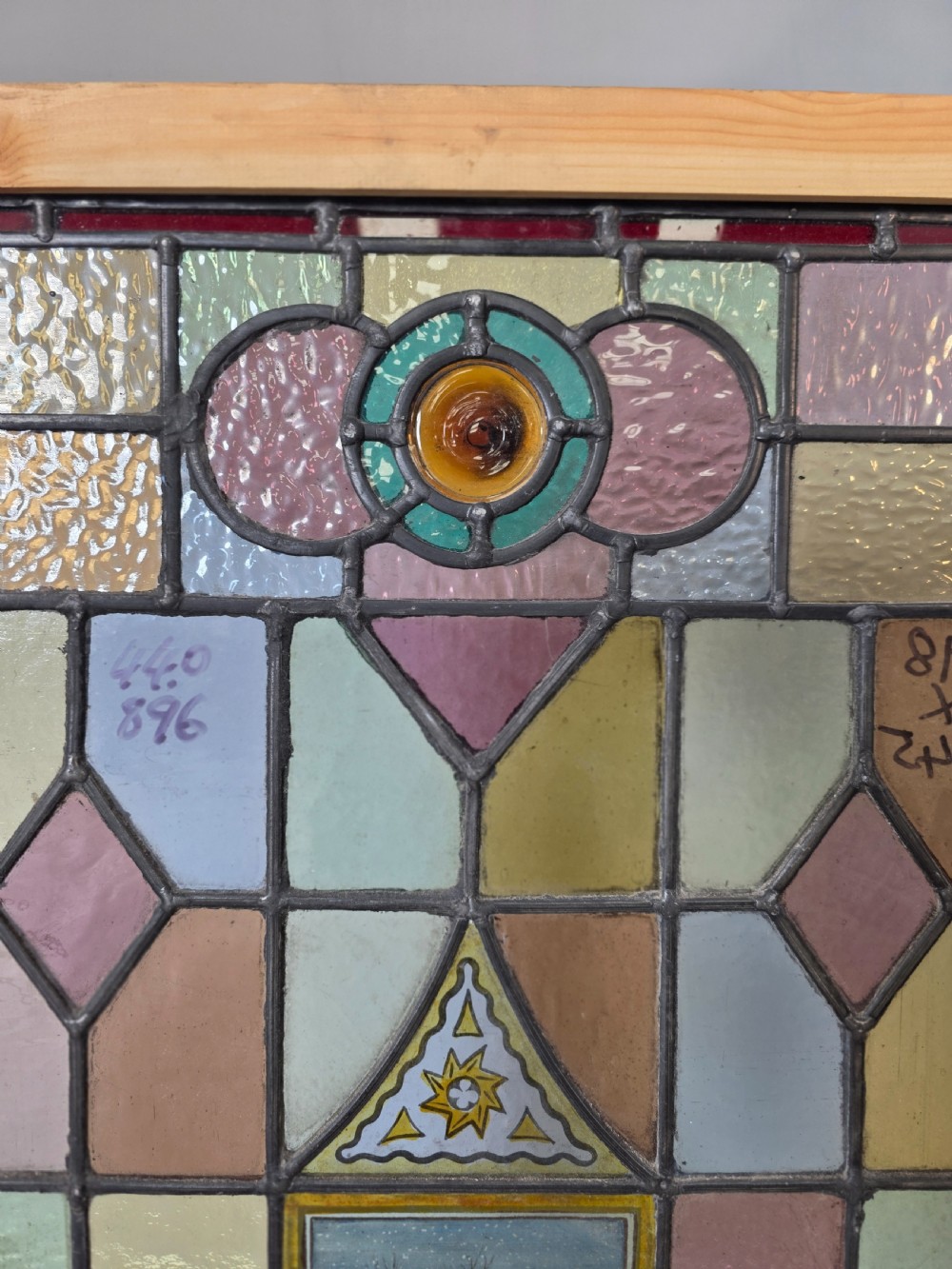 A rectangular Edwardian leaded stained glass window panel featuring geometric coloured glass, roundels, and a central hand-painted winter landscape scene set in a pine frame. View III