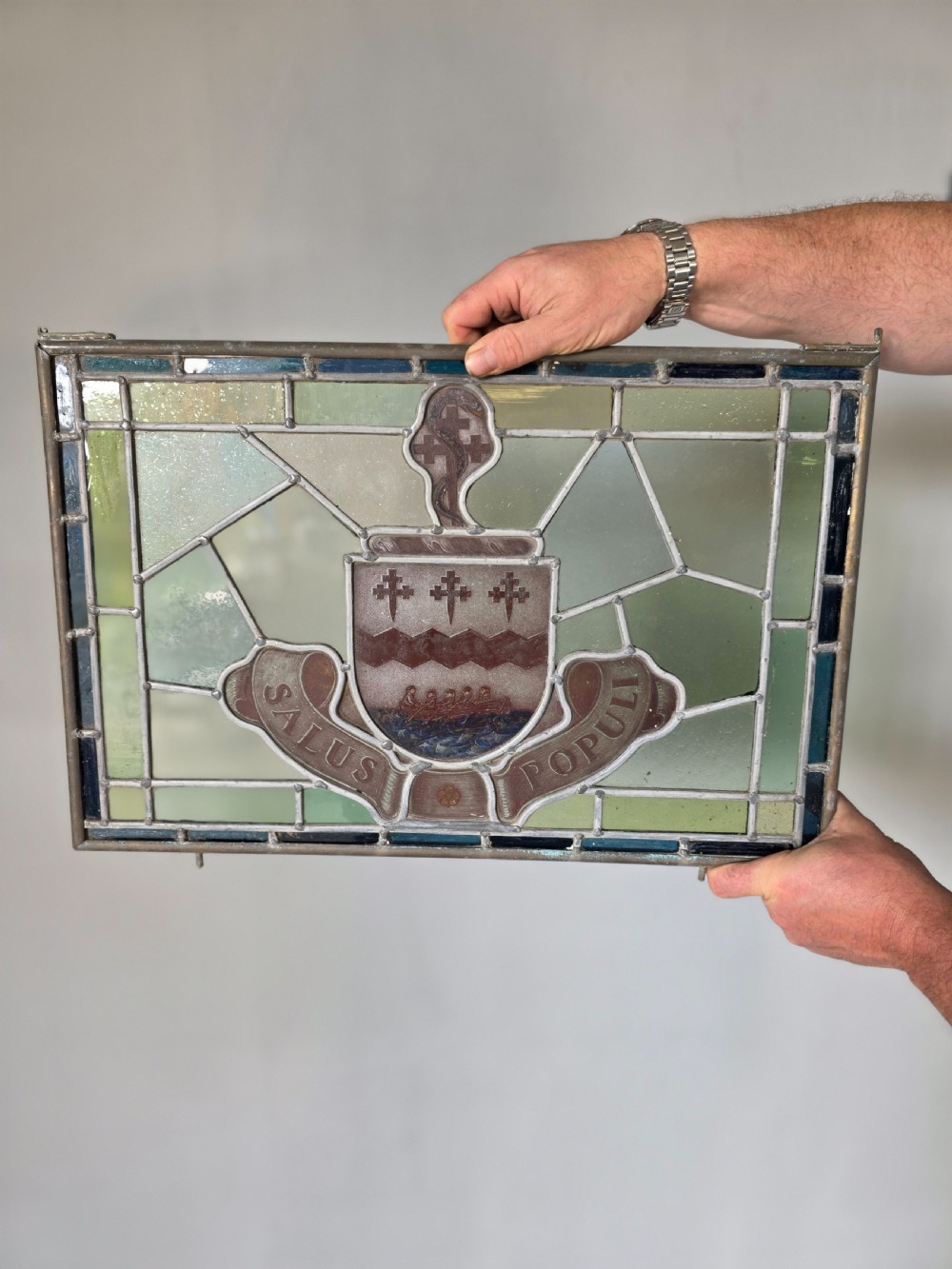A rectangular Victorian leaded glass window panel featuring a central hand-painted heraldic coat of arms with the Latin motto Salus Populi. View IV