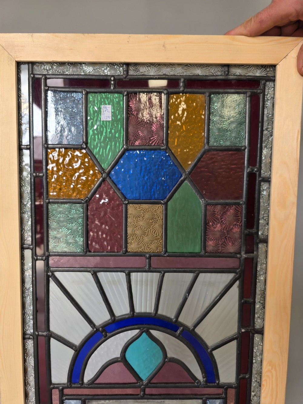 An elongated rectangular leaded glass panel featuring a central hand-painted landscape scene surrounded by geometric coloured glass borders. View IV